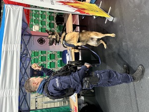 Zdjęcie przedstawia umundurowanego policjanta oraz psa służbowego.