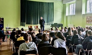 Zdjęcie przedstawia umundurowanego policjanta w klasie pełnej uczniów.