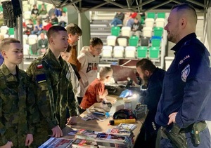 Zdjęcie przedstawia uczniów szkoły przy stoisku profilaktycznym przygotowanym przez sosnowieckich policjantów.