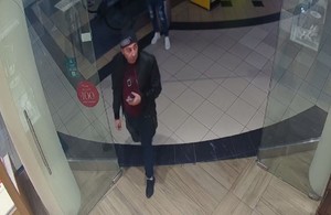 Zdjęcie przedstawia mężczyznę w czarnej kurtce i czapce na terenie sklepu jubilerskiego.