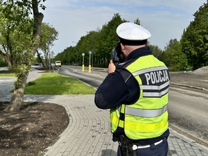 Zdjęcie przedstawia umundurowanego policjanta mierzącego prędkość.