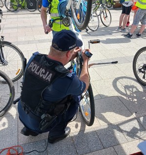 Zdjęcie przedstawia umundurowanego policjanta grawerującego rower.