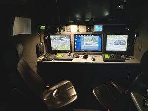 Zdjęcie przedstawia wnętrze Ruchomego Stanowiska Dowodzenia, gdzie widoczne są trzy monitory oraz zapisy.