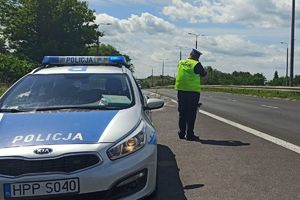 Zdjęcie przedstawia policjanta przy radiowozie