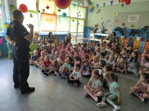 Zdjęcie przedstawia umundurowanego policjanta prowadzących prelekcję oraz dzieci.