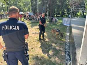 Zdjęcie przedstawia dwóch, umundurowanych policjantów  z psem służbowym.