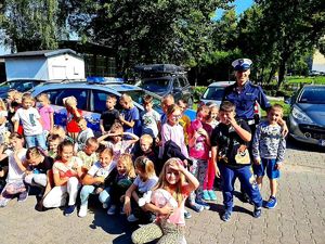 Zdjęcie przedstawia umundurowaną policjantkę pozującą do zdjęcia z grupą uczniów.