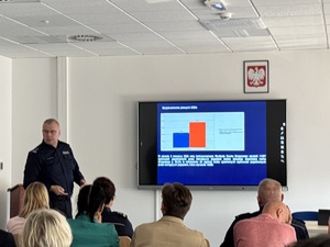 Zdjęcie przedstawia Komendanta Miejskiego Policji w Sosnowcu omawiającego prezentację podczas Komisji Bezpieczeństwa i Porządku Publicznego Rady Miejskiej w sosnowieckiej komendzie.
