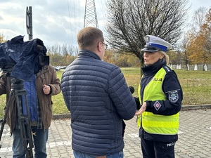 Zdjęcie przedstawia umundurowaną policjantkę udzielającą informacji mediom.