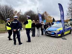 Zdjęcie przedstawia umundurowanych policjantów oraz grupę dzieci. W tle radiowóz.