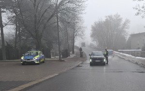 Zdjęcie przedstawia umundurowanego policjanta wydziału ruchu drogowego sprawdzającego trzeźwość kierowcy.