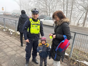 Zdjęcie przedstawia kobietę z dzieckiem oraz umundurowanego policjanta.