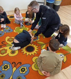 Zdjęcie przedstawia umundurowanego policjanta z przedszkolakami.