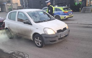 Zdjęcie przedstawia umundurowanego policjanta sprawdzającego trzeźwość kierowcy samochodu marki Toyota.