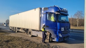 Zdjęcie przedstawia policjanta oraz funkcjonariusza Inspekcji Transportu Drogowego kontrolujących pojazd ciężarowy.