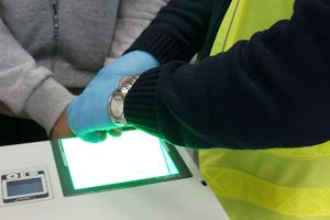 Zdjęcie przedstawia policyjnego technika kryminalistyki oraz zatrzymanego podczas czynności.