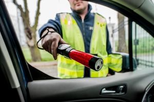 Zdjęcie przedstawia umundurowanego policjanta z urządzeniem alcosensor.