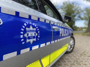Zdjęcie przedstawia oznakowany radiowóz policyjny i napis &quot;Pomagamy i chronimy Policja 112&quot;.