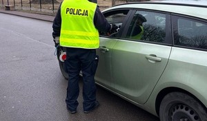 Zdjęcie przedstawia umundurowanego policjanta badającego trzeźwość kierującego.