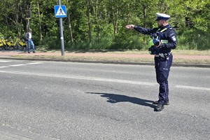 Zdjęcie przedstawia umundurowanego policjanta wydziału ruchu drogowego podczas działań.
