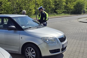 Zdjęcie przedstawia dwóch umundurowanych policjantów wydziału ruchu drogowego przy samochodzie marki Skoda.