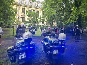 Zdjęcie przedstawia dwa, oznakowane motocykle służbowe oraz uczestników festynu.