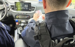Zdjęcie przedstawia umundurowanego policjanta ruchu drogowego podczas czynności służbowych.
