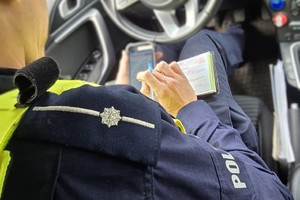 Zdjęcie przedstawia umundurowanego policjanta ruchu drogowego podczas czynności służbowych.