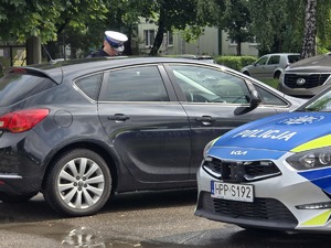 Zdjęcie przedstawia umundurowanego policjanta ruchu drogowego podczas czynności służbowych.