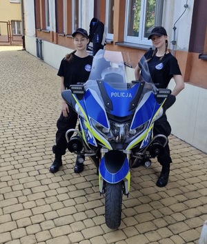 Zdjęcie przedstawia dwie dziewczyny pozujące do zdjęcia z motocyklem służbowym.