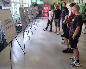 Zdjęcie przedstawia umundurowanego policjanta oraz uczniów na korytarzu.