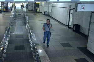 Na zdjęciu widoczny jest mężczyzna ubrany w szarą koszulkę i spodnie dżinsowe rozmawiający przez telefon komórkowy