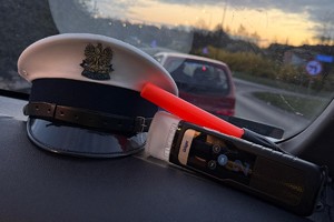 Zdjęcie przedstawia policyjną czapkę, latarkę oraz urządzenie do badania trzeźwości
