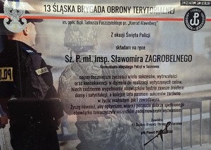 Zdjęcie przedstawia podziękowanie o treści: &quot;13 ŚLĄSKA BRYGADA OBRONY TERYTORIALNE

Im. ppłk dypl. Tadeusza Puszczyńskiego ps. Konrad Wawelberg
z okazji Święta Policji
składam na ręce
Sz. P.mł.insp. Sławomira ZAGROBELNEGO Komendanta Miejskiego Policji w Sosnowcu

najserdeczniejsze życzenia wielu sukcesów, wytrwałości oraz konsekwencji w dążeniu do realizacji wytyczonych celów. Niech codzienne wypełnianie obowiązków będzie zawsze źródłem dumy i satysfakcji, a kolejne lata pasmem sukcesów zarówno w życiu osobistym jak i zawodowym. Życzę również, aby optymizm, wiara i poczucie dobrze spełnionego obowiązku towarzyszyły wszystkim podejmowanym wyzwaniom.

Dowódca
13 Śląskiej Brygady Obrony Terytorialnej&quot;