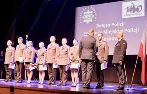Zdjęcie przedstawia umundurowanych policjantów podczas uroczystości na scenie.