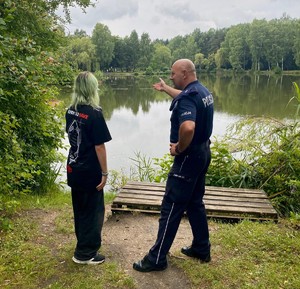 Zdjęcie przedstawia umundurowanego policjanta oraz przedstawiciela WOPR podczas kontroli zbiorników wodnych.