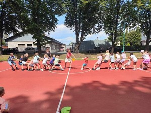Zdjęcie przedstawia grupę dzieci na boisku podczas zabawy.
