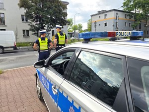 Zdjęcie przedstawia umundurowanych policjantów oraz oznakowany radiowóz.