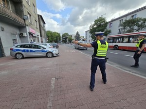 Zdjęcie przedstawia dwóch umundurowanych policjantów podczas kontroli drogowej.