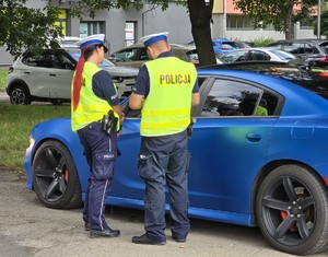 Zdjęcie przedstawia umundurowaną policjantkę oraz policjanta podczas kontroli drogowej.