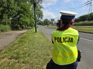 Zdjęcie przedstawia umundurowaną policjantkę mierzącą prędkość.
