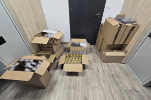 Zdjęcie przedstawia tekturowe pudła z zawartością papierosów oraz plastikowych butelek z żółtymi nakrętkami.