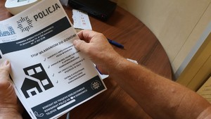 Zdjęcie przedstawia kobietę trzymającą w rękach ulotkę.