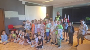 Zdjęcie przedstawia umundurowanych policjantów z grupą dzieci w sali szkolnej.