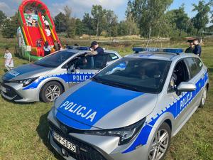 Zdjęcie przedstawia umundurowanych policjantów oraz radiowozy służbowe.