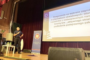 Zdjęcie przedstawia umundurowanego policjanta na scenie.