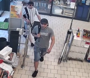 Zdjęcie przedstawia dwóch mężczyzn w czarnych czapkach z daszkiem na terenie sklepu.