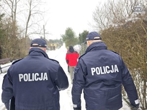 Zdjęcie przedstawia dwóch, umundurowanych policjantów na terenie ogródków działkowych.