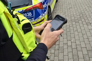 Zdjęcie przedstawia umundurowanego policjanta Wydziału Ruchu Drogowego podczas czynności służbowych.