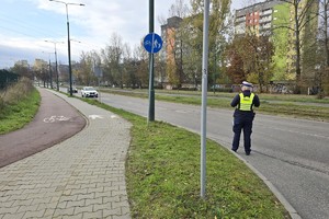 Zdjęcie przedstawia umundurowanego policjanta Wydziału Ruchu Drogowego podczas czynności służbowych.
